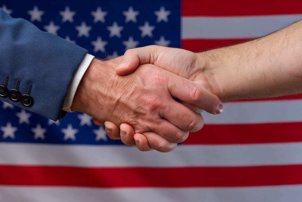 two,men,shaking,hands,with,the,united,states,flag,in