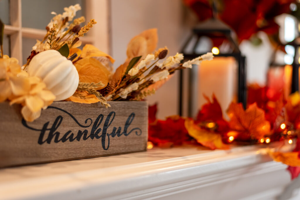 fall holiday mantel decorated with colorful leaves and twinkle lights